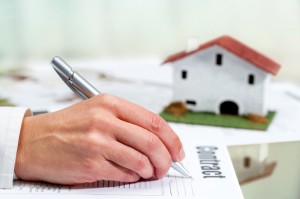 Hand filling out house buying contract.